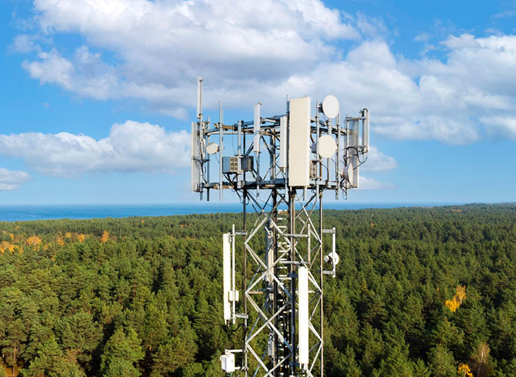 telecommunication tower with antennas for 5g network on forest and blue sky background